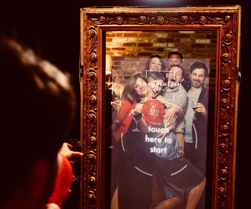 Image shows - party guests posing in front of the Magic Selfie Mirror